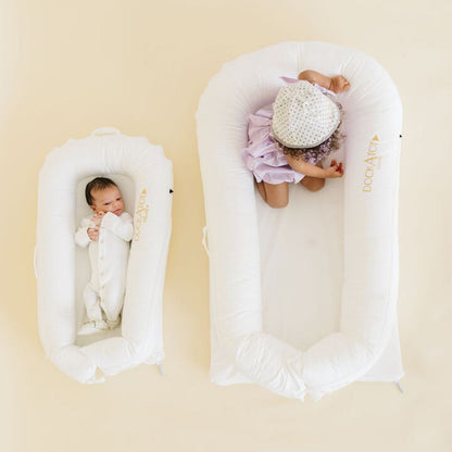 赤ちゃん2人が並んでDockATotでくつろぐシーン（DeluxeとGrandサイズ比較）