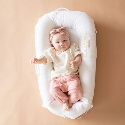 DockATot（プリスティンホワイト）で赤ちゃんがリラックスしている様子（ピンク背景）